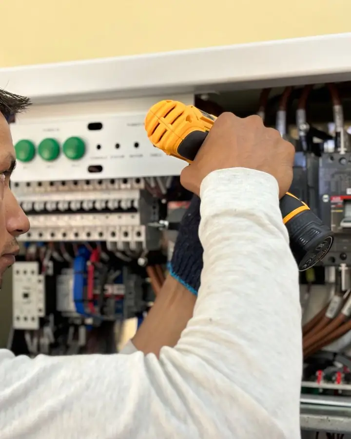 An electrician working on a breaker panel