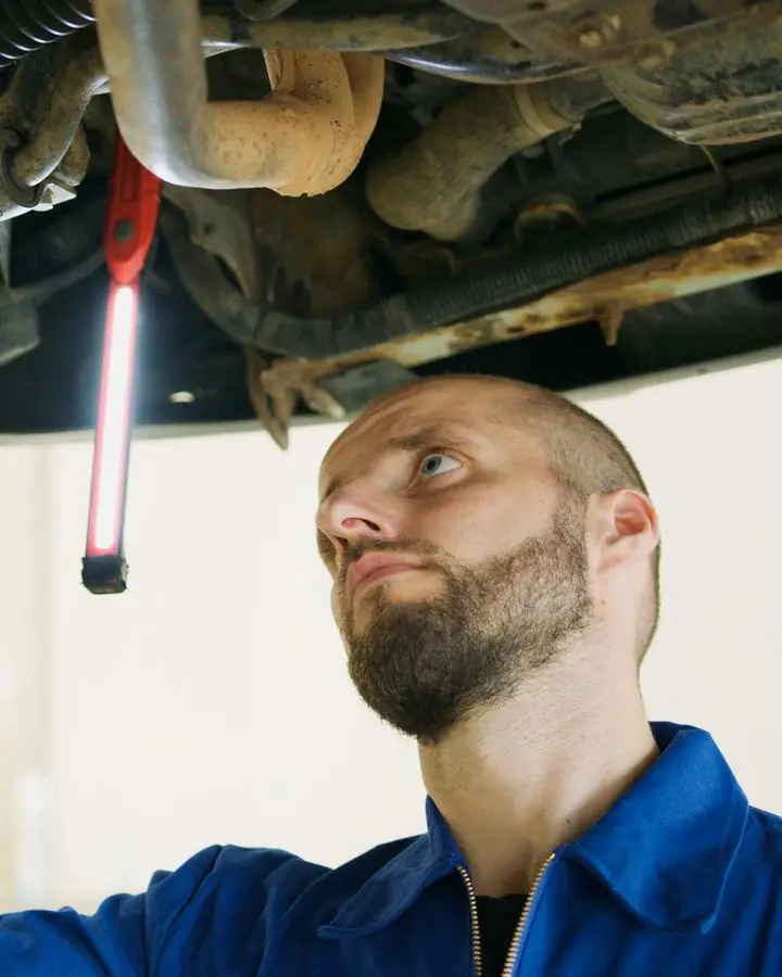 A mechanic checking under a car